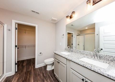 A bathroom with a toilet, sink, and mirror.