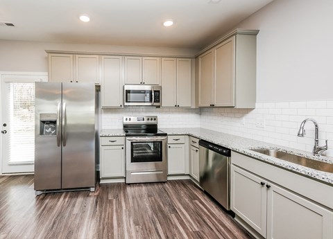 A modern kitchen with wooden floors and stainless steel appliances.