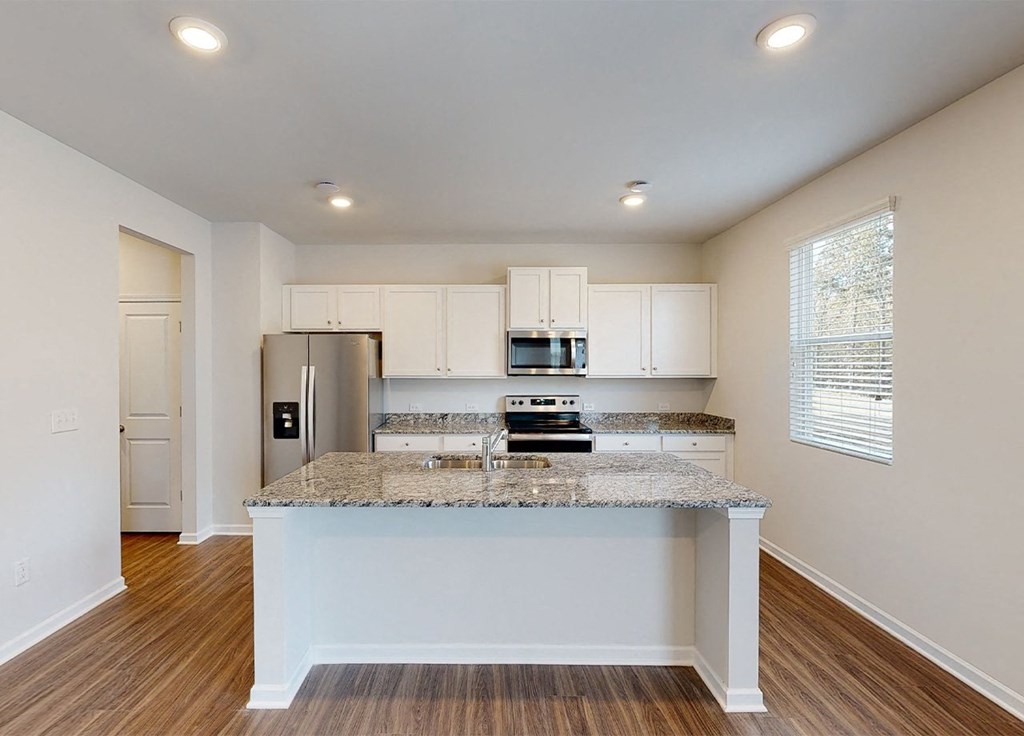 A kitchen with a granite countertop and white cabinets.