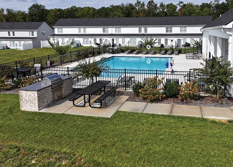 A pool surrounded by a black fence and a stone bench.