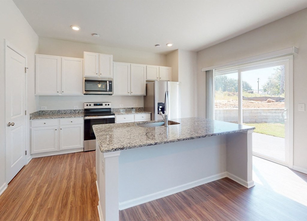 A kitchen with white cabinets and a granite countertop.