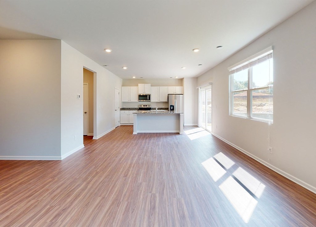 A spacious kitchen with wooden floors and white walls.