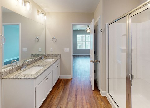 A bathroom with a sink, mirror, and wooden floors.