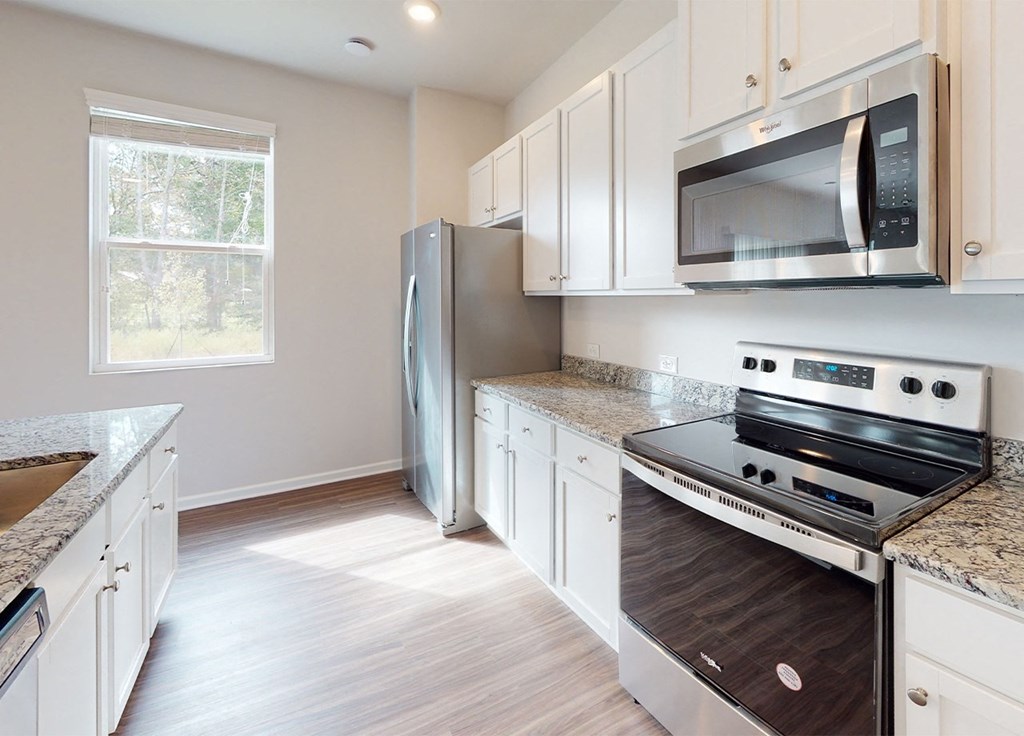 A kitchen with a stainless steel refrigerator, microwave, and oven.
