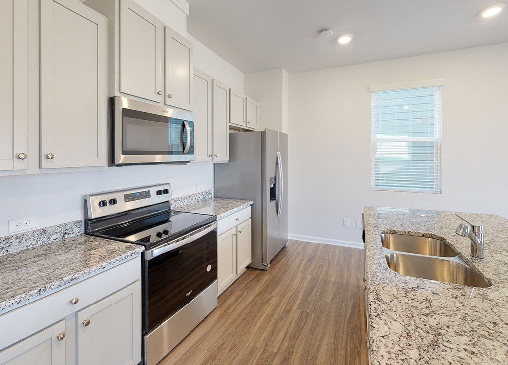 A kitchen with a stove, microwave, and refrigerator.