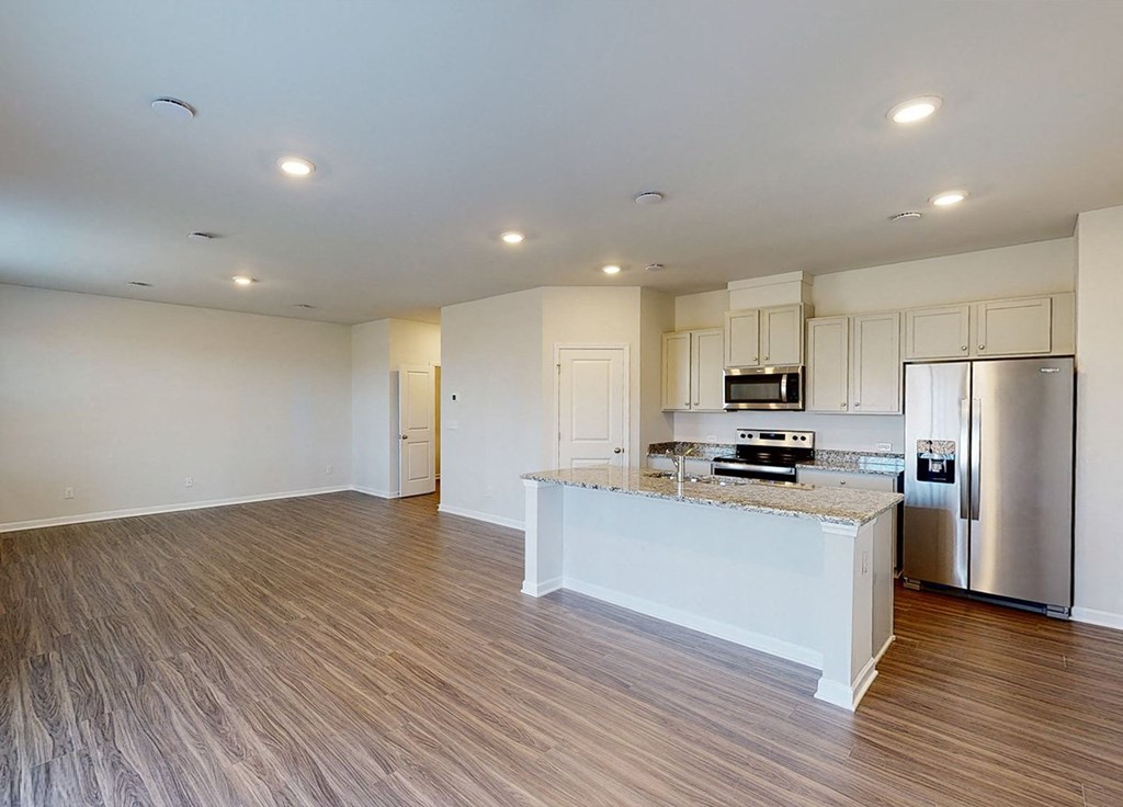 A kitchen with a refrigerator, microwave, and oven.