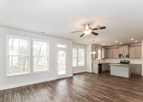 A spacious kitchen and living room with wood flooring and white walls.