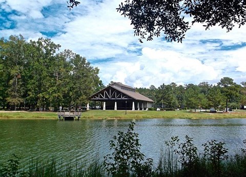 A large building sits by a body of water with a dock leading to it.