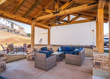 a covered patio with couches and chairs under a wooden roof