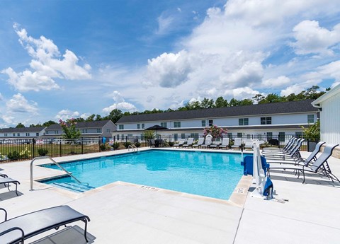 A swimming pool with lounge chairs and a building in the background.