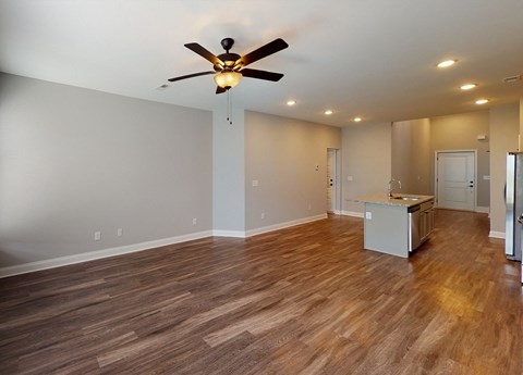 A room with a ceiling fan and wooden flooring.