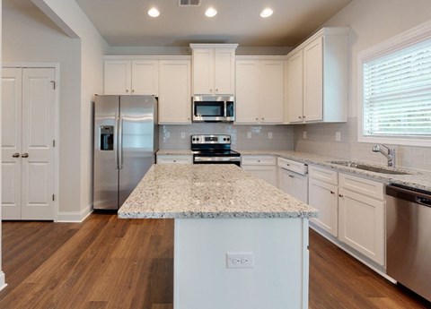 A kitchen with a granite countertop and stainless steel appliances.