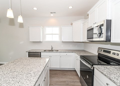 A kitchen with white cabinets and granite countertops.
