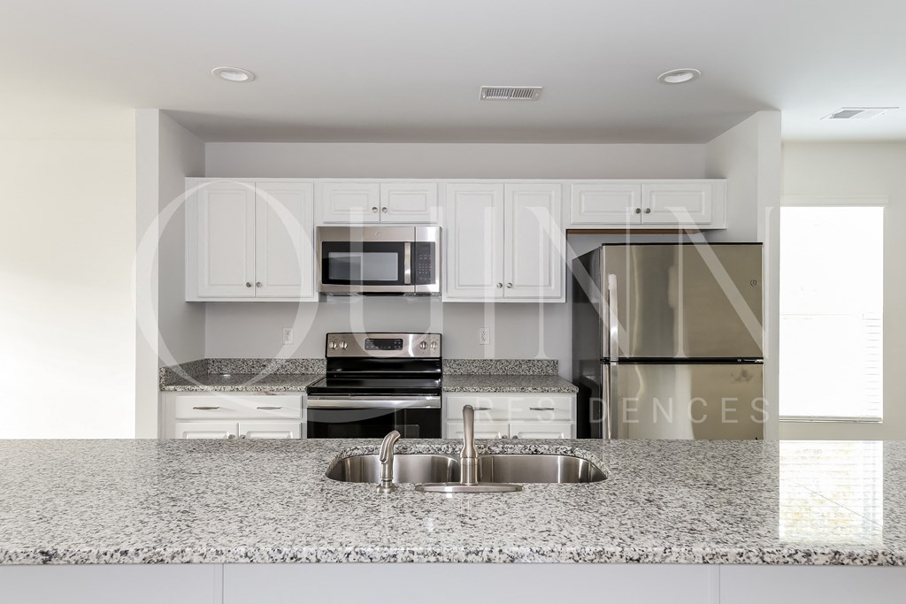 a kitchen with granite countertops and white cabinets