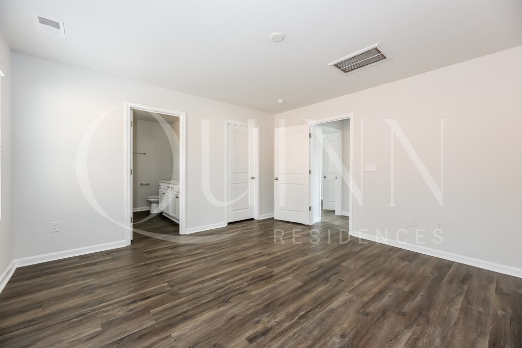 a bedroom with hardwood floors and white walls