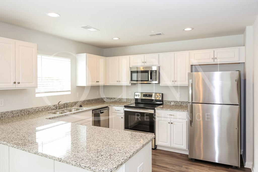 a kitchen with white cabinets and granite countertops