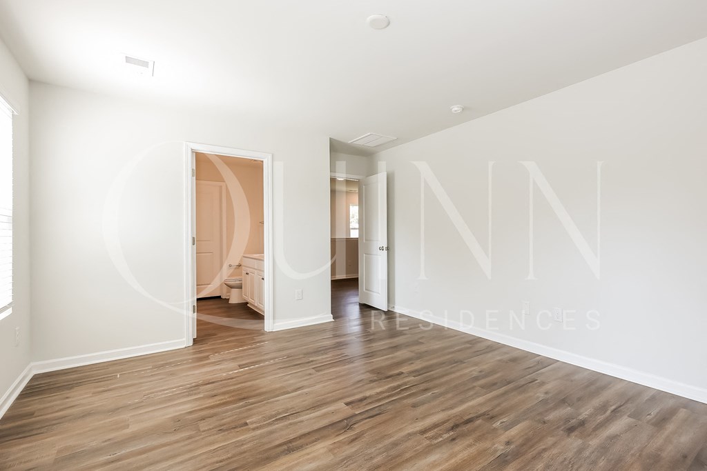 a bedroom with hardwood floors and white walls