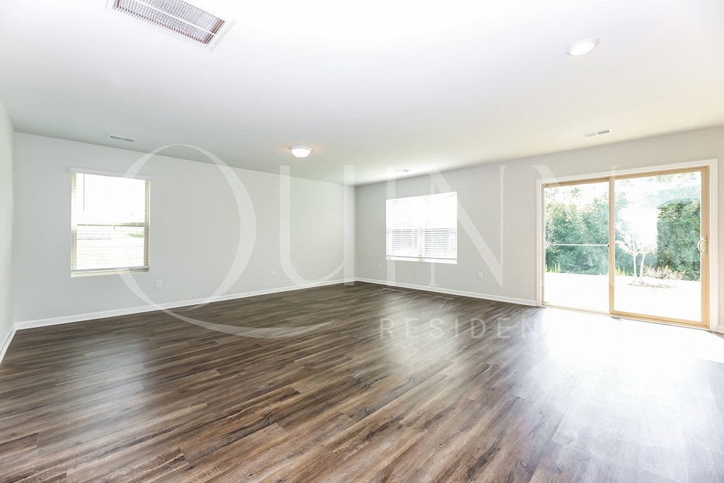 an empty living room with hardwood floors and a sliding glass door