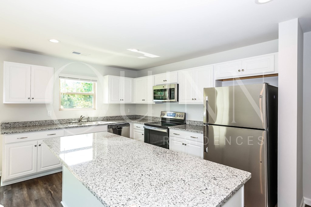 a kitchen with white cabinets and granite countertops