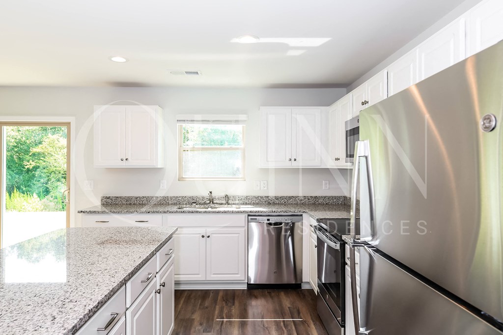 a kitchen with white cabinets and granite countertops