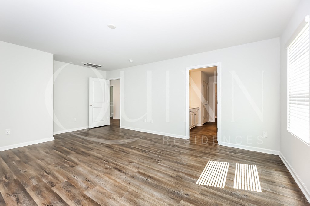 a bedroom with hardwood floors and white walls