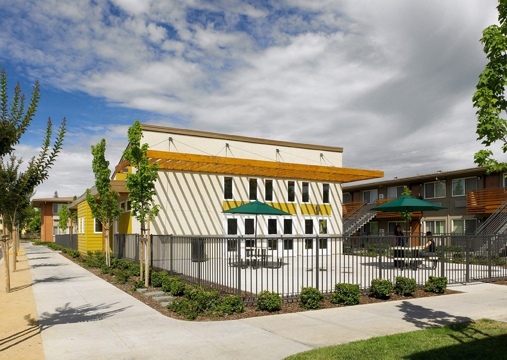 a building with a white and yellow facade and a black and white fence in front of it