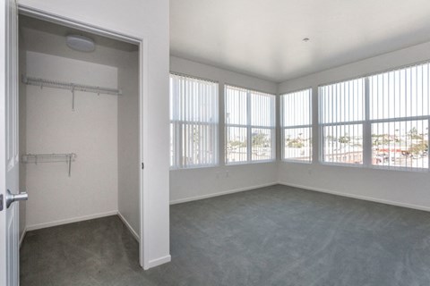 an empty living room with large windows and a closet