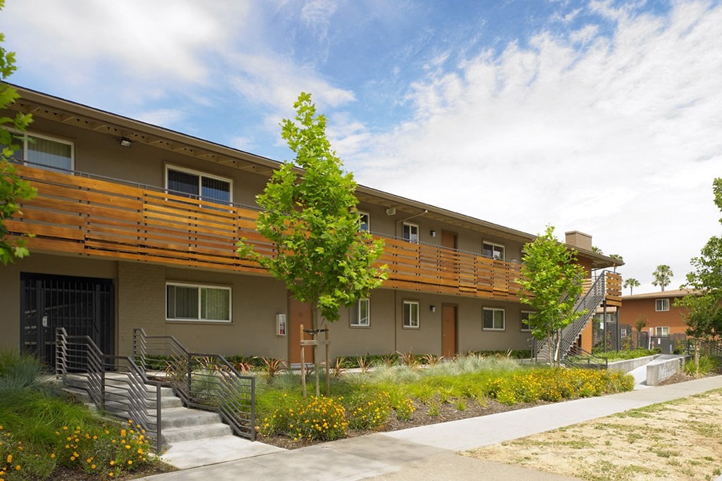a building with a wooden balcony and a grassy area in front of it
