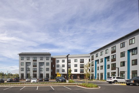 A parking lot in front of a building with a blue sky in the background.
