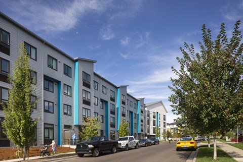 A row of modern apartment buildings with cars parked in front.