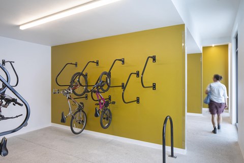 A yellow wall with bicycles hanging on it.
