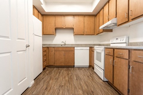an empty kitchen with wooden cabinets and white appliances