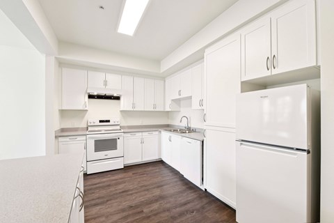 A white kitchen with a refrigerator on the right.