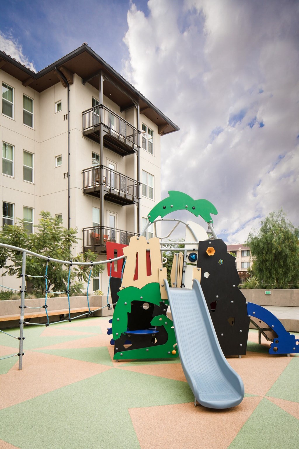 a playground at an apartment building with a jungle gym and slides