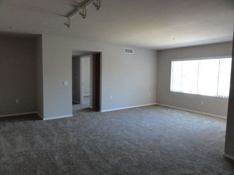 an empty living room with white walls and a window