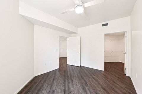 A room with a ceiling fan and wood flooring.