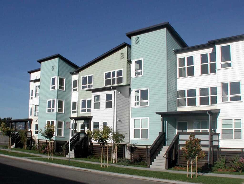 a row of green and white houses on the side of a street