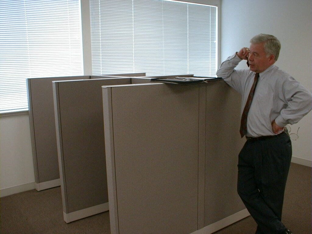 an old man standing next to a filing cabinet in an office