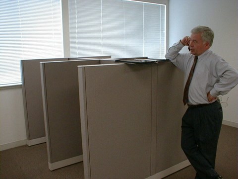 an old man standing next to a filing cabinet in an office
