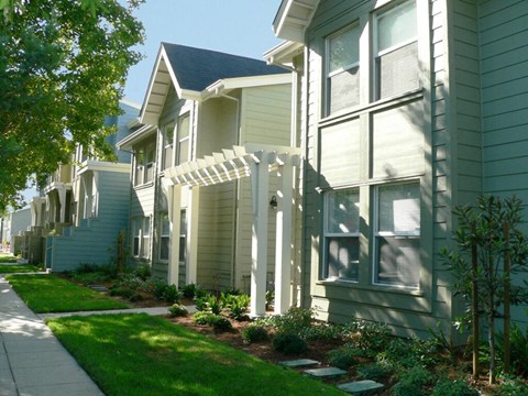 a row of houses with a white arbor in front of a sidewalk