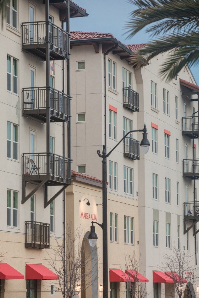 a building with red umbrellas in front of it and a palm tree