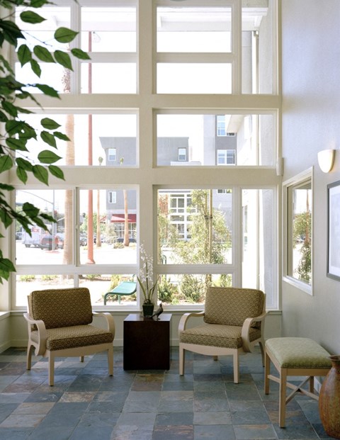 a lobby with chairs and a table and large windows