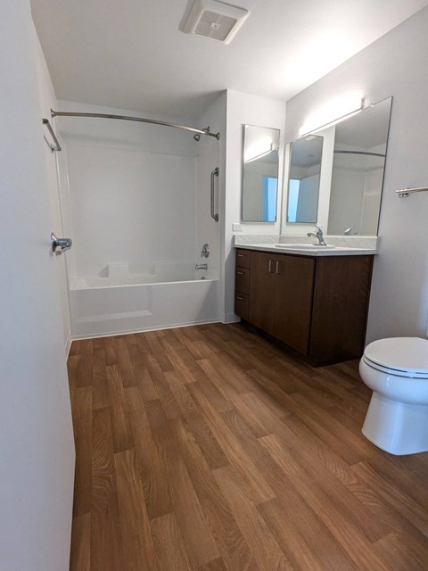 A white bathroom with a wooden floor and a white toilet.