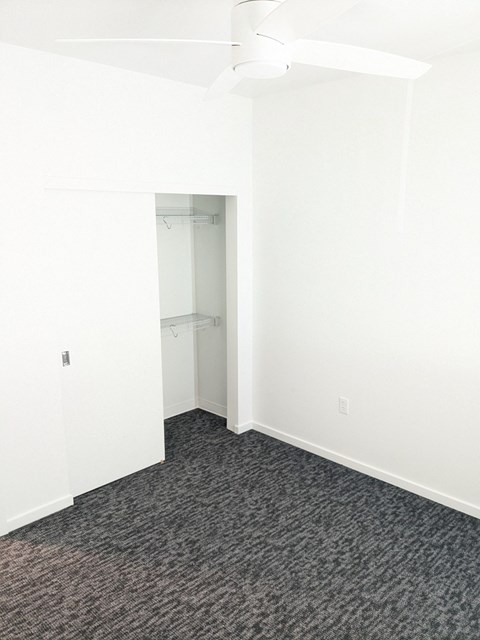 A room with a ceiling fan and carpeted floor.