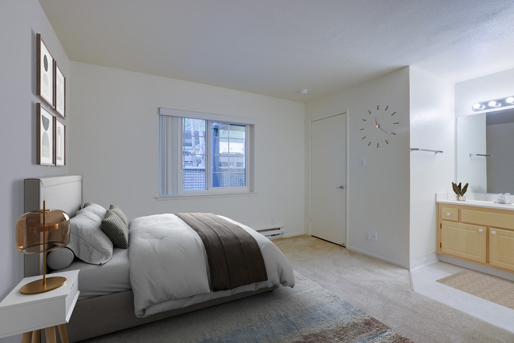 a bedroom with a bed and a bathroom with a clock on the wall