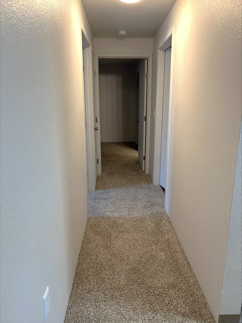 A long hallway with carpeted floors and white walls.