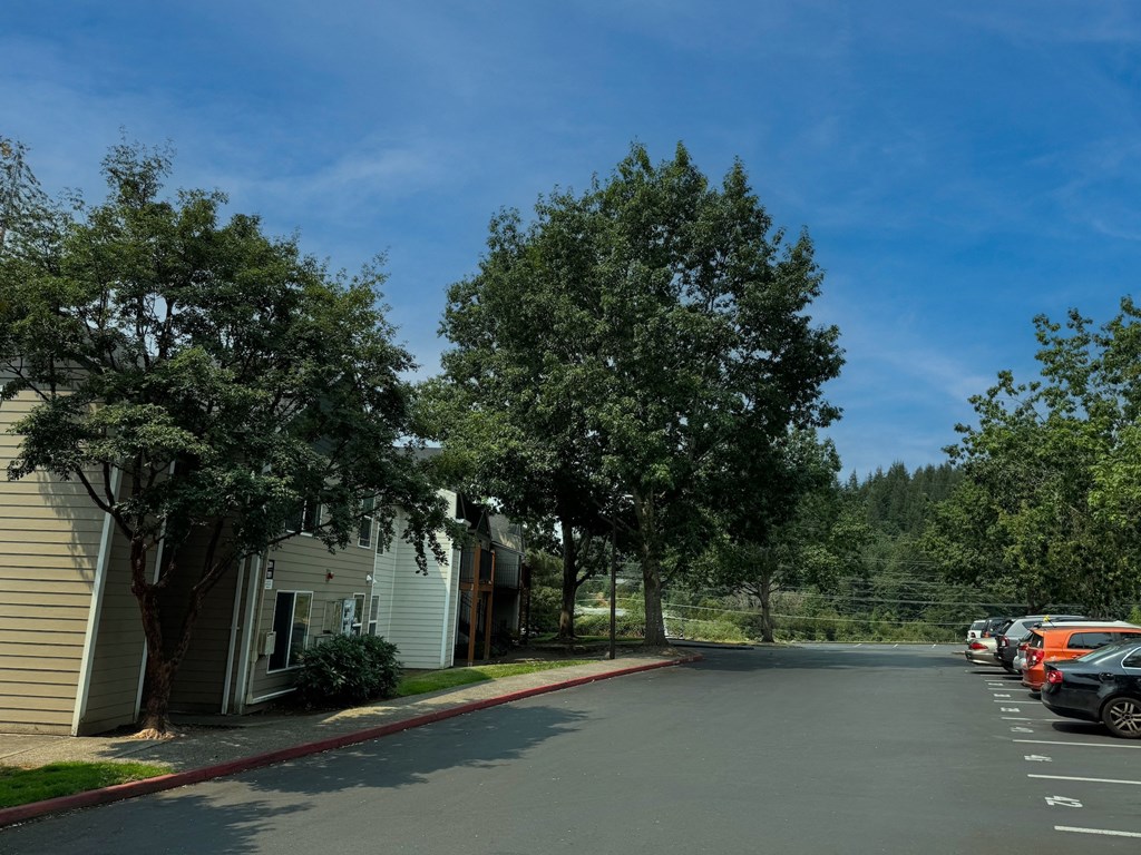 a parking lot with houses and trees on the side of a street