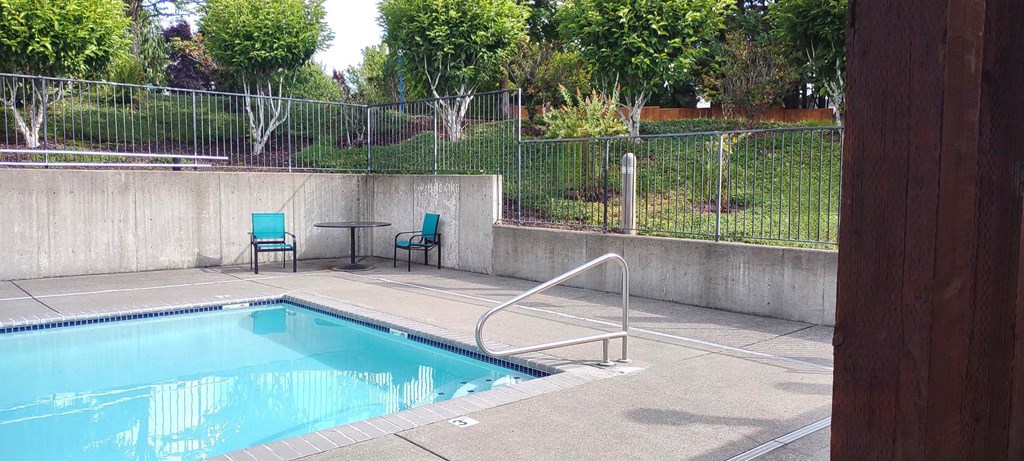 a swimming pool with chairs and a fence around it