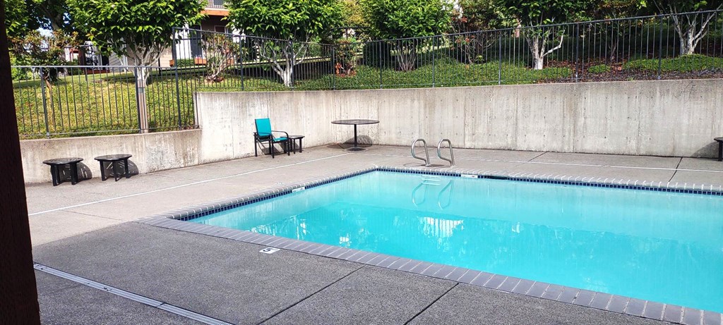 a swimming pool with chairs and a table next to it