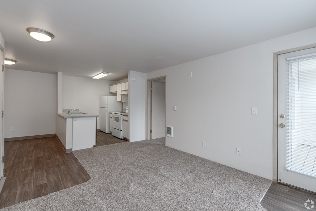 A spacious living room with a kitchen in the background.